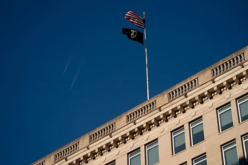 علم أمريكي يرفرف بجانب علم خاص بالمحاربين القدامى فوق مبنى، يعكس قضايا الصحة النفسية للمحاربين.