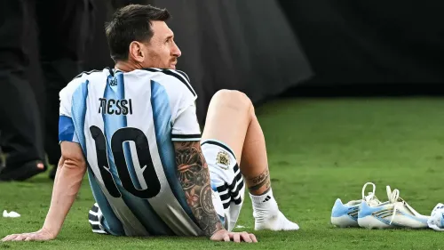ليونيل ميسي يجلس على أرض الملعب بإحباط بعد خسارة الأرجنتين في نهائي كأس العالم 2022 ضد إسبانيا، مرتديًا قميص رقم 10.