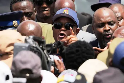 وزير الشرطة السابق سينزو متشونو يتحدث بحماس وسط حشد من الناس، مع وجود قوات أمنية في الخلفية، في سياق مزاعم فساد.