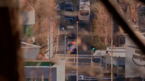 مشهد لسيارات الشرطة والمركبات الأخرى تتجه نحو مركز احتجاز الرئيس الكوري الجنوبي المعزول يون سوك يول، مع وجود أشجار في الخلفية.