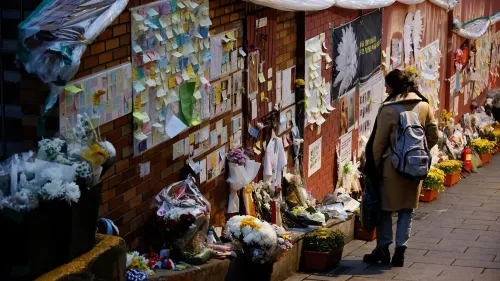 امرأة واقفة أمام جدار مغطى بالورود وبطاقات التعازي، في موقع حادث التدافع المميت في إيتايون، سيول.