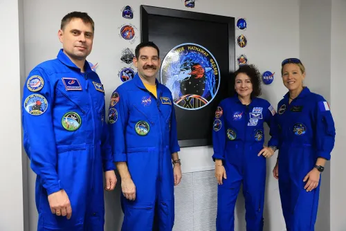 أربعة رواد فضاء يرتدون بدلات زرقاء يقفون أمام شعار المهمة Crew-12، استعدادًا للانطلاق إلى محطة الفضاء الدولية.