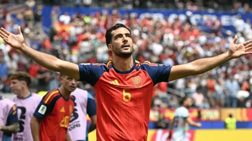 لاعب منتخب إسبانيا يرتدي القميص الأحمر برقم 6 يرفع ذراعيه احتفالاً في ملعب مليء بالجماهير خلال كأس العالم 2026.