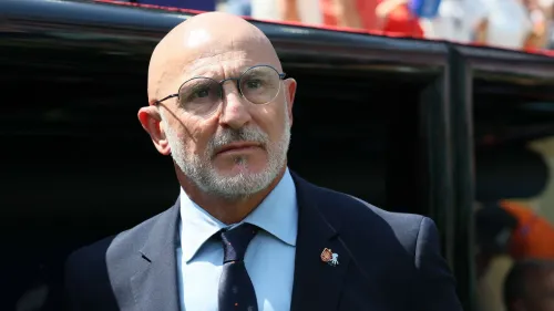 لويس دي لا فوينتي مدرب منتخب إسبانيا يرتدي بدلة رسمية ونظارات، يعبر عن ثقته بفوز لاعب إسباني بالكرة الذهبية هذا العام.