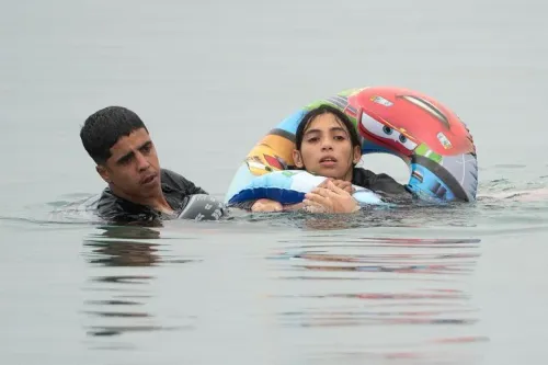 شاب يساعد فتاة تحمل عوامة سباحة أثناء عبورهما البحر نحو سبتة في موجة الهجرة غير النظامية من المغرب.