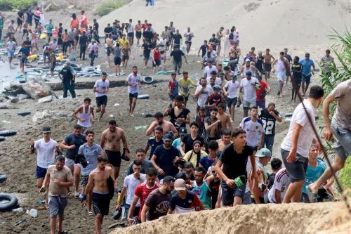 مهاجرون يعبرون شاطئ سبتة في محاولة دخول إسبانيا خلال موجة اقتحام جماعي غير مسبوقة من المغرب، وسط أزمة هجرة كبيرة.