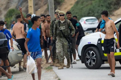 جندي إسباني وسط مجموعة من المهاجرين غير النظاميين على شاطئ سبتة خلال أزمة الهجرة الجماعية في يوليو 2023.