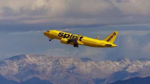 طائرة Spirit Airlines الصفراء تحلق فوق جبال مغطاة بالثلوج، تعبيرًا عن إعادة هيكلة ديون الشركة والخروج من الإفلاس.