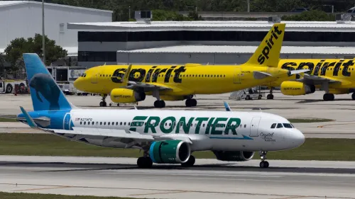 طائرة تابعة لشركة فرونتير تحمل شعارها الملون، بينما تظهر طائرات سبيريت الصفراء في الخلفية، مما يعكس المنافسة بين الشركتين.
