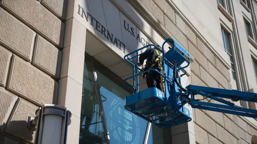 عمال يقومون بإزالة لافتة الوكالة الأمريكية للتنمية الدولية من مبنى، في سياق إعادة هيكلة الوزارة.