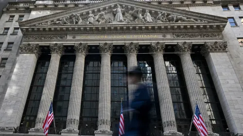 واجهة بورصة نيويورك مع أعمدة ضخمة وأعلام أمريكية، تعكس التوترات الاقتصادية بعد انتقادات ترامب لرئيس الاحتياطي الفيدرالي.