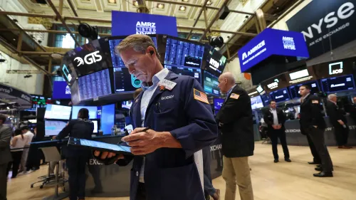 تاجر في بورصة نيويورك يتفاعل مع البيانات الاقتصادية، مع وجود شاشات تعرض مؤشرات السوق في الخلفية.