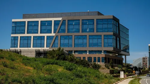 مبنى شركة Stripe الحديث يتكون من نوافذ زجاجية كبيرة محاط بالأشجار، يعكس التطورات في قطاع التكنولوجيا والتسريح الأخير للموظفين.