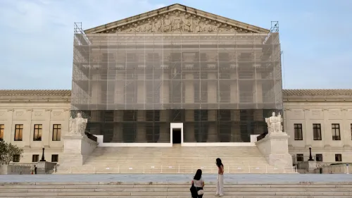 واجهة المحكمة العليا الأمريكية مغطاة بشبكة، مع وجود زوار يقفون على الدرجات. تعكس الصورة التغييرات القانونية الحالية في سياسة الهجرة.