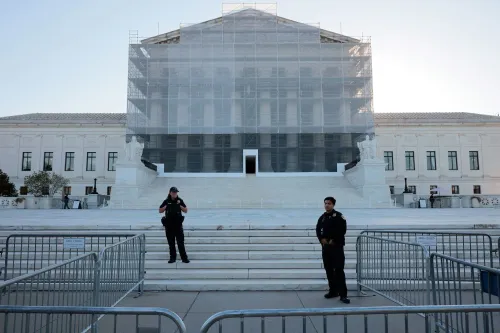 مدخل المحكمة العليا الأمريكية محاط بسياج أمني، مع وجود ضباط شرطة يتواجدون في الموقع، بينما يتم تغطية المبنى بأقمشة.