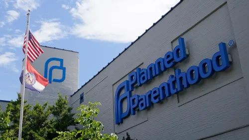 مبنى منظمة "بلانيد باريثود" يبرز في الصورة، مع العلم الأمريكي وعلم ولاية ميسوري يرفرفان أمامه، مما يعكس النقاش حول تمويل الرعاية الصحية.