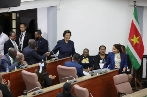 انتخاب جينيفر غيرلنغز-سيمونز كأول رئيسة لسورينام في البرلمان، حيث تبتسم وتصافح الأعضاء وسط أجواء احتفالية.