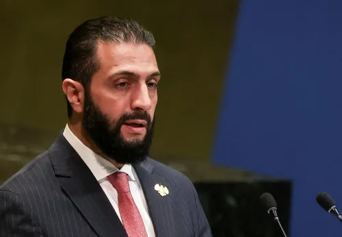 رجل يتحدث في مؤتمر، يعبر عن أهمية الانتخابات البرلمانية في سوريا كخطوة نحو الانتقال السياسي بعد الحرب.