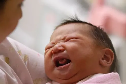 طفل حديث الولادة يبكي في حضن والدته، مما يعكس التحديات التي تواجهها تايوان في زيادة معدلات المواليد.