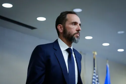 جاك سميث، المستشار الخاص السابق، يظهر بملابس رسمية في مؤتمر صحفي، مع خلفية تتضمن أعلامًا أمريكية، معبرًا عن آرائه حول القضايا القانونية المتعلقة بترامب.