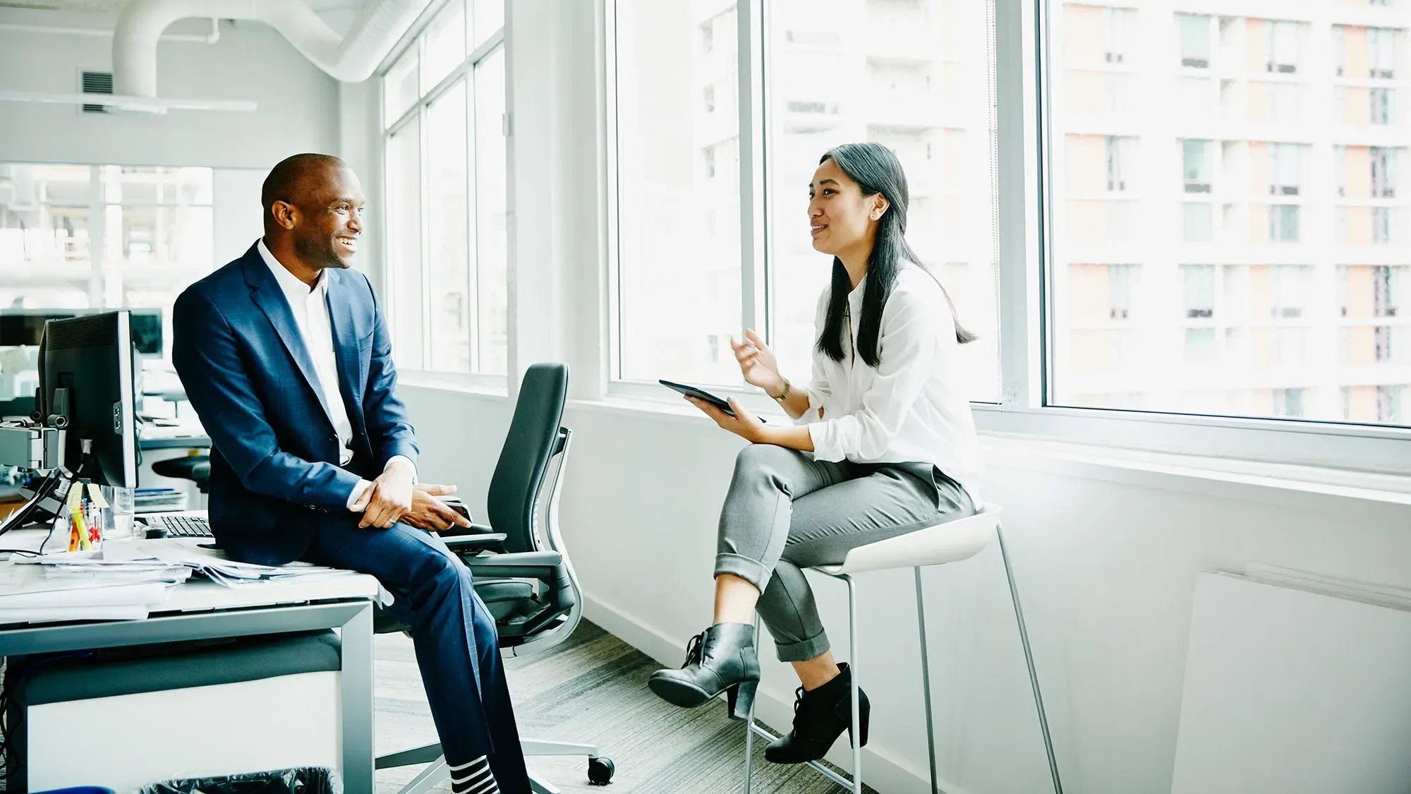 محادثة بين رجل وامرأة في مكتب حديث، حيث يتبادلان الحديث بشكل ودي، مما يعكس أهمية التواصل الاجتماعي.