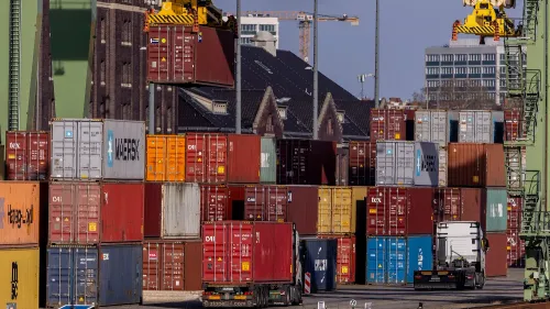 حاويات شحن ملونة في ميناء، تُظهر تأثير الحرب التجارية بين الاتحاد الأوروبي والولايات المتحدة، مع التركيز على الرسوم الجمركية المرتفعة.