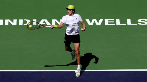 جواو فونسيكا، لاعب تنس برازيلي شاب، يضرب الكرة خلال مباراة في بطولة إنديان ويلز، مع خلفية ملعب البطولة.