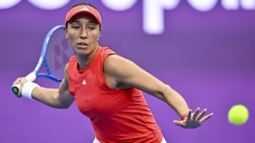 جيسيكا بيجولا، نجمة التنس الأمريكية، في لحظة حماسية خلال مباراة، مع كرة التنس في الهواء، تستعد لضربة قوية.