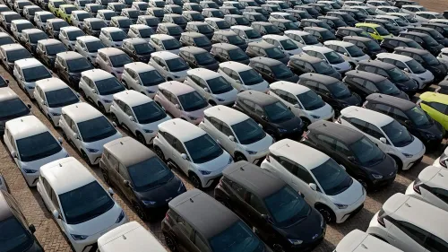 مجموعة كبيرة من سيارات BYD الكهربائية متراصة في ساحة انتظار، تظهر تنوع الألوان والتصاميم، مما يعكس نجاح الشركة في السوق.