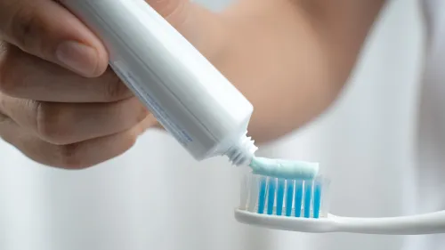 عبوة معجون أسنان تُستخدم لوضع معجون بالفلورايد على فرشاة أسنان، مما يبرز أهمية الفلورايد في صحة الفم للأطفال.