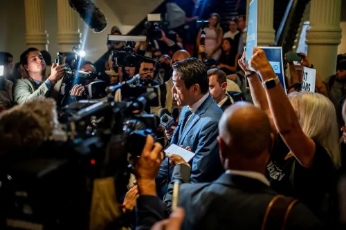 مؤتمر صحفي يعقده سياسي في تكساس وسط حشد من الصحفيين والمحتجين، مع لافتات تعبر عن آراء مختلفة حول إعادة تقسيم الدوائر الانتخابية.