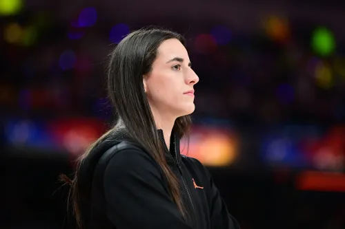 نجمة كرة السلة كيتلين كلارك تتأمل في مباراة، وسط أضواء الملعب، في سياق قضية المطاردة التي تعرضت لها.