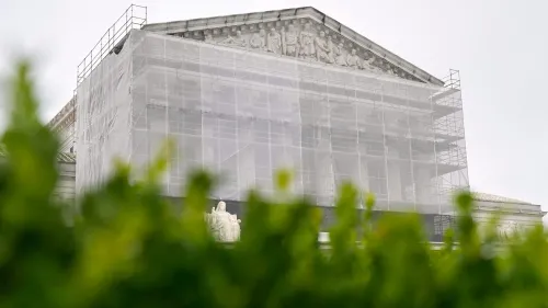 واجهة مبنى المحكمة العليا الأمريكية مغطاة بشبكة حماية أثناء أعمال الترميم، مع تمثال بارز في المقدمة.