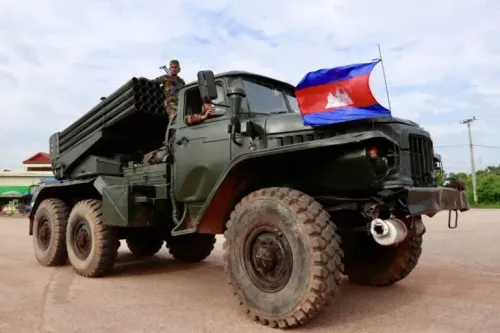 عربة عسكرية كمبودية مزودة بصواريخ، يقف عليها جنديان، مع العلم الكمبودي يرفرف في الخلفية، في سياق التوترات الحدودية مع تايلاند.