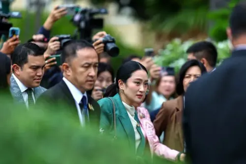 رئيسة وزراء تايلاند بايتونغتارن شيناواترا تتجه نحو المحكمة محاطة بمساعدين وصحفيين، وسط توتر سياسي بسبب اتهامات قانونية.