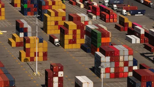 حاويات شحن ملونة مرتبة في ساحة شحن، تعكس تأثير التعريفات الجمركية على التجارة الأمريكية.