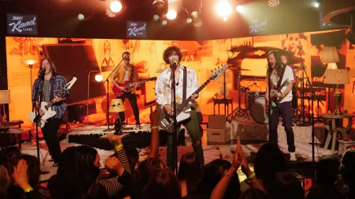 فرقة All-American Rejects تؤدي على المسرح في عرض مباشر، مع تفاعل الجمهور في خلفية مفعمة بالطاقة.