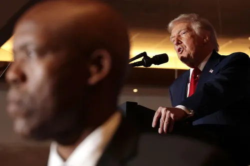 ترامب يتحدث في حدث عام، مع وجود شخص آخر في الخلفية. تعكس الصورة التوترات حول الهجرة والمواقف تجاه المجتمع الصومالي.