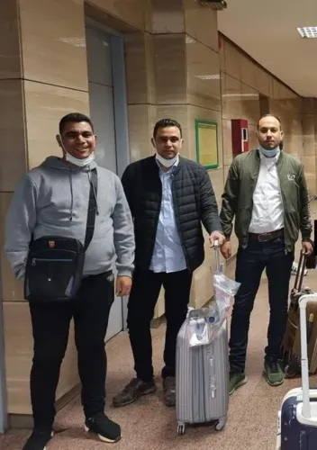 مجموعة من ثلاثة رجال مصريين في مطار، يحملون حقائب سفر. يعكس المشهد روح المغامرة والبحث عن فرص جديدة في تنزانيا.