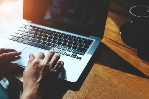 شخص يستخدم جهاز كمبيوتر محمول في بيئة عمل، مما يعكس تأثير التكنولوجيا والذكاء الاصطناعي على سوق العمل.