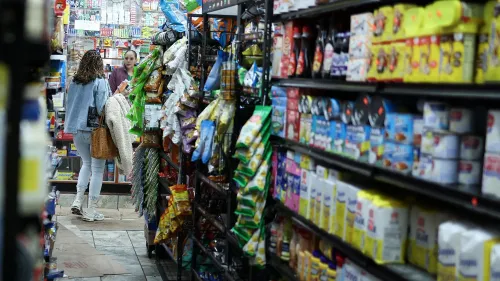 امرأتان تتسوقان في ممر متجر مليء بالمنتجات الغذائية، مع التركيز على تراجع إنفاق المستهلكين في يناير.