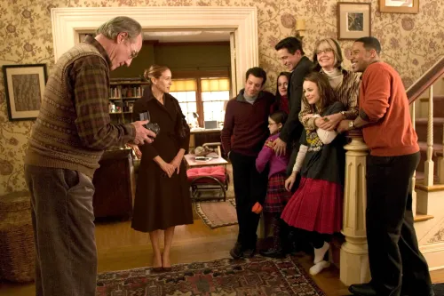 مشهد عائلي من فيلم "حجر العائلة"، يظهر أفراد العائلة مجتمعين في غرفة معيشة دافئة، يتبادلون الابتسامات واللحظات السعيدة.