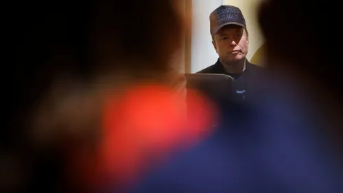 إيلون ماسك يرتدي قبعة ويظهر في خلفية مشوشة، مما يعكس قلقه بشأن إدارة الحكومة وتأثيرها على الصحة العامة.