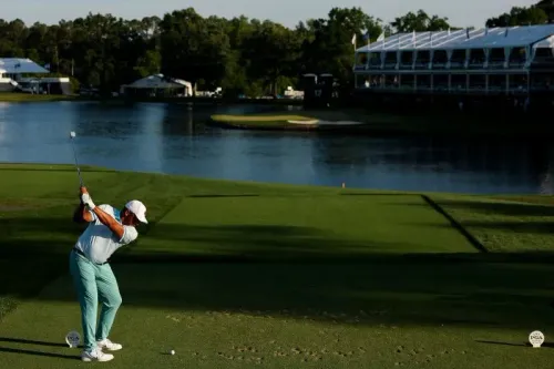 لاعب غولف يقوم بتسديدة على الحفرة 17 في ملعب كويل هولو، مع وجود المياه خلفه ومرافق البطولة في الخلفية.