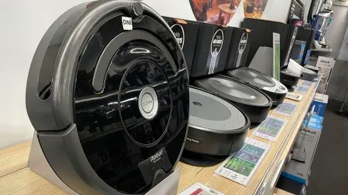 تظهر الصورة مجموعة من المكانس الكهربائية الروبوتية من شركة iRobot، بما في ذلك طراز Roomba، المعروض في متجر.