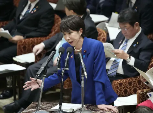 سناء تاكايتشي، وزيرة اليابان، تتحدث في البرلمان حول التوترات مع الصين بشأن تايوان، بينما يظهر الحضور في الخلفية.