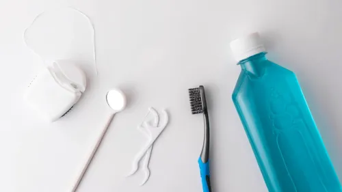 أدوات نظافة الفم تشمل فرشاة أسنان، خيط، مرآة، وغسول فم، مما يعكس أهمية روتين العناية بالأسنان للحفاظ على صحة الفم.