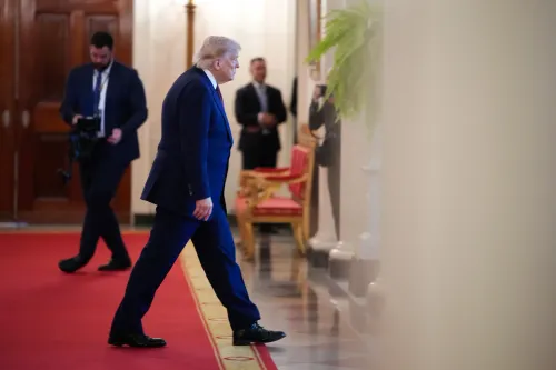 دونالد ترامب يسير في ممر رسمي، محاطًا بعناصر أمنية، مما يعكس أجواء التوتر السياسي حول الحرب مع إيران.