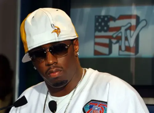 شون "ديدي" كومبس يتحدث في مؤتمر صحفي، مرتديًا قبعة ونظارات شمسية، مع شعار قناة MTV خلفه، في سياق برنامج "Making the Band".