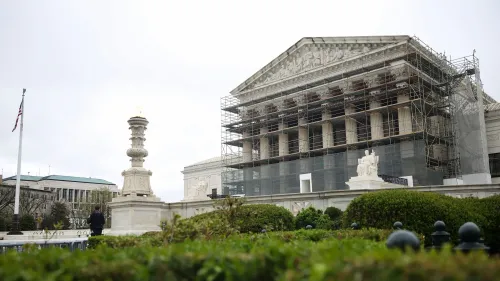 مبنى المحكمة العليا الأمريكية محاط بأعمال الترميم، مع وجود سياج حول الواجهة. يظهر العلم الأمريكي في الخلفية.